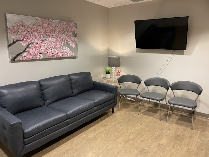 Modern IV therapy clinic waiting room with black couch and TV.